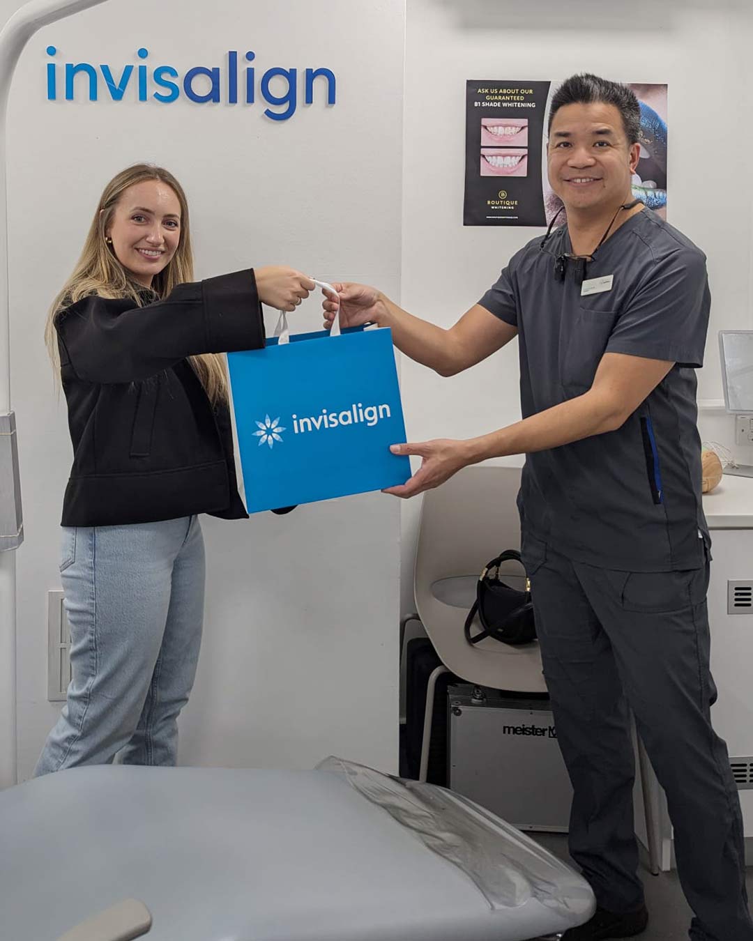 Dr Ed Young with a patient holding an Invisalign gift bag in the clinic